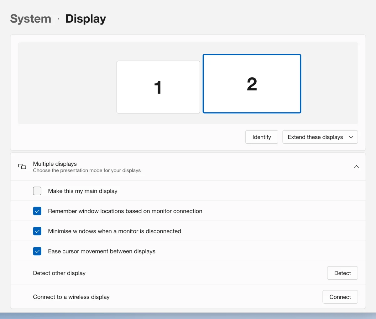 A drawn picture of Windows 11 Settings at System, Display, with displays 1 and 2 side by side and display 2 selected, and Multiple displays open below with the Make this my main display tick box first; the tick box is outlined.